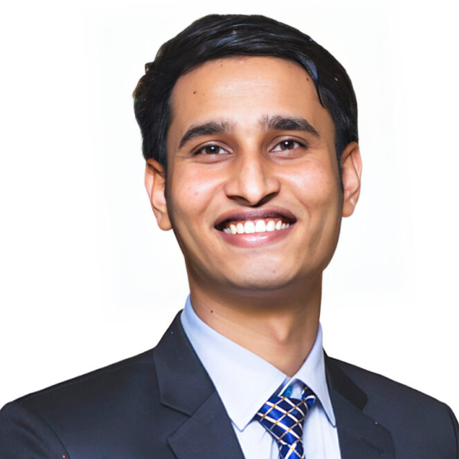 Smiling man in a dark suit and blue patterned tie against a white background (professional headshot).
