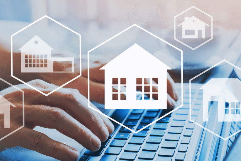 Hands typing on a laptop with white hexagonal house icons overlay, signaling smart home tech or real estate connectivity.