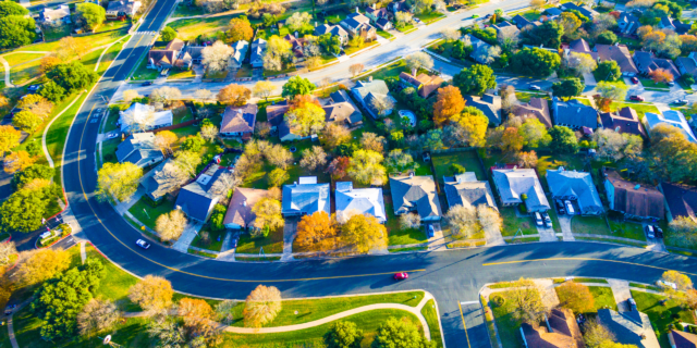 LJHHL Blog_Cash Rate Update _Aug 2026 Aerial view of a suburban neighborhood with curved roads, green lawns, and tree-lined houses from above.