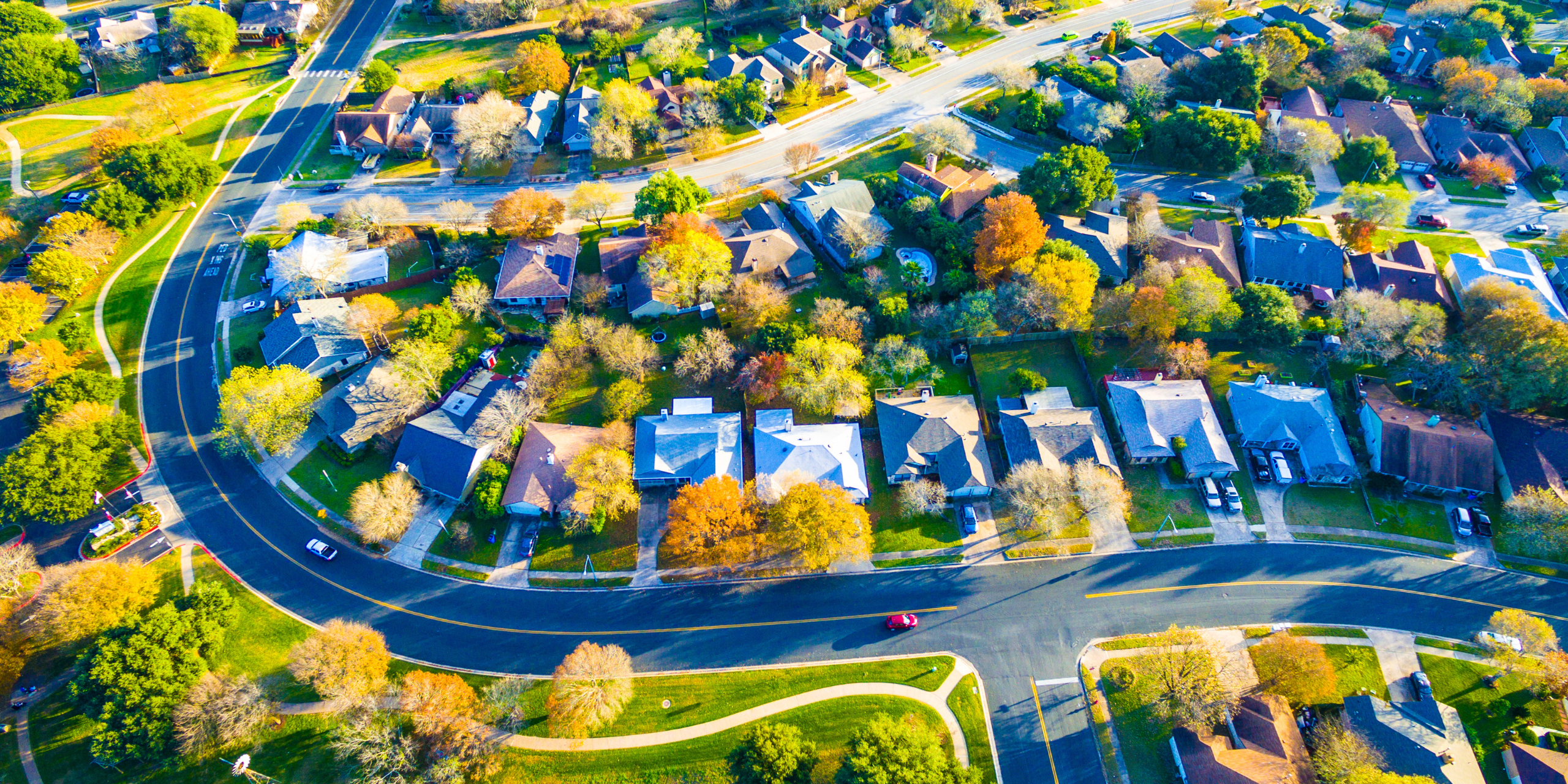 LJHHL Blog_Cash Rate Update _Aug 2026 Aerial view of a suburban neighborhood with curved roads, green lawns, and tree-lined houses from above.